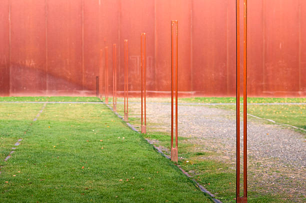 symbolic and ghostly view to the Berlin wall (1961-1989) with rusty steel poles on green frass in autumn 2011